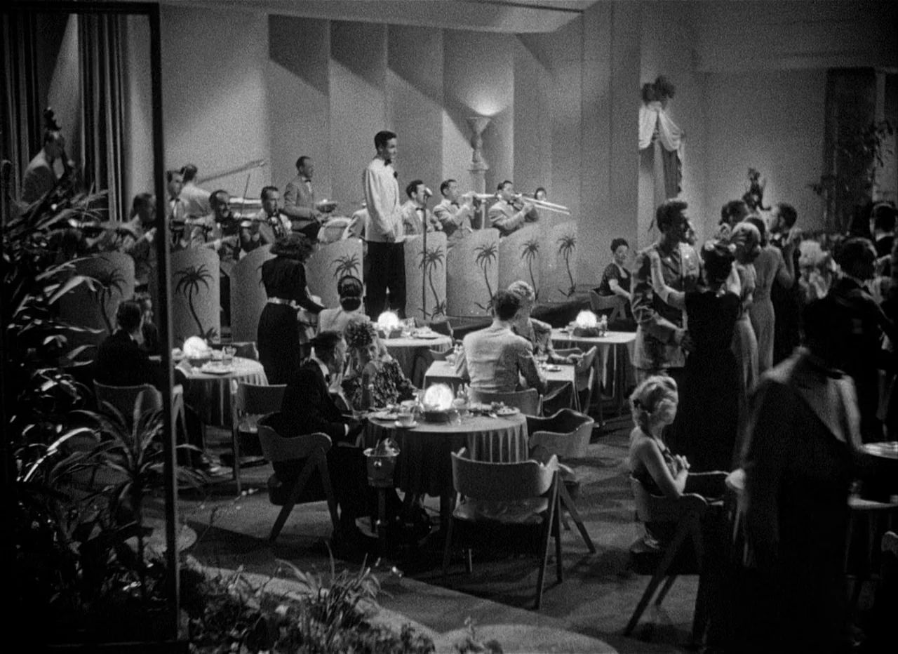 Dead Reckoning (1946) movie still: wide — A spacious 1940s nightclub features multiple circular dining tables arranged on a polished floor. An…