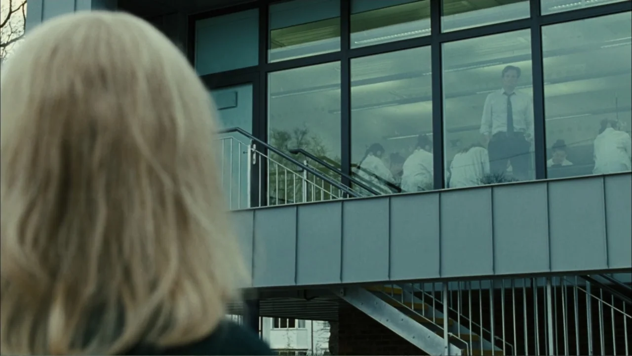 Before I Go to Sleep (2014) movie still: medium — A modern building exterior features a large glass-enclosed upper-level classroom seen from…