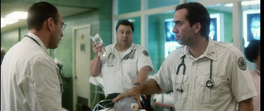 Bringing Out The Dead (1999) movie still: medium — A clinical hospital corridor with green tiled walls and bright ceiling fluorescent lights. Three…