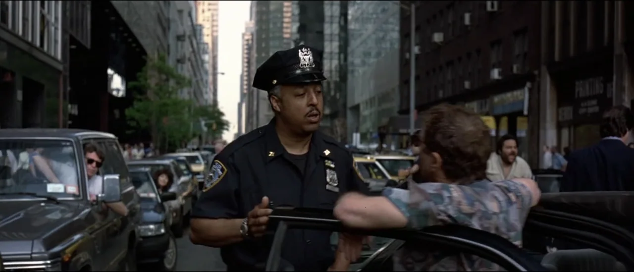 The Peacemaker (1997) movie still: medium — A busy New York City street features lines of cars and tall office buildings. A police officer in…