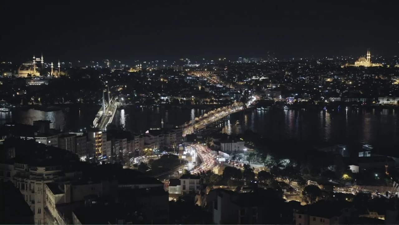 A Gift from God (2019) movie still: establishing — A wide aerial view of Istanbul at night featuring the Golden Horn and bridges. The cityscape is…