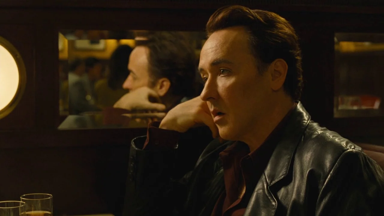 Love & Mercy (2014) movie still: medium — A dark, wood-paneled booth inside an establishment with an integrated wall mirror. A man sits alone with…