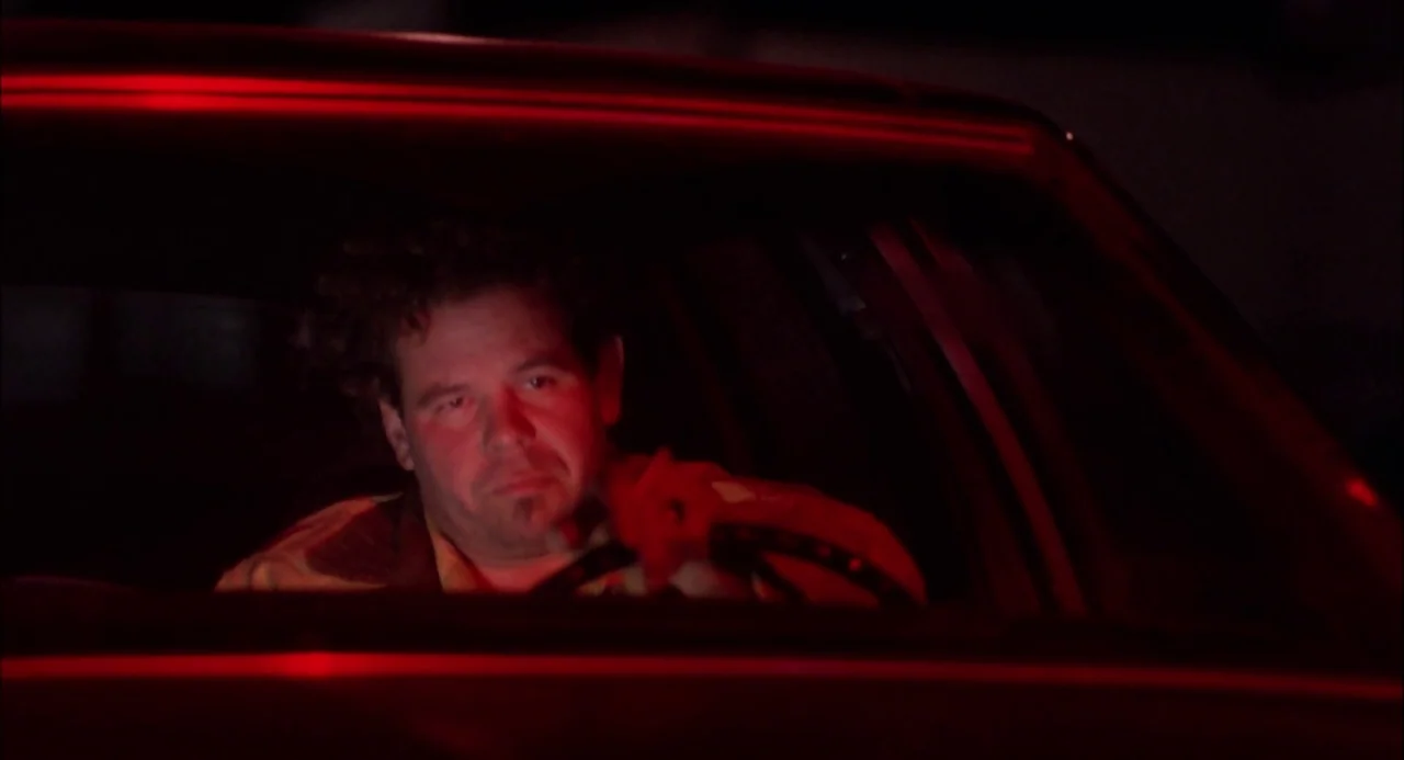 Trees Lounge (1996) movie still: medium — A man sits in the driver seat of a vehicle at night. The interior is illuminated by a sharp red light.