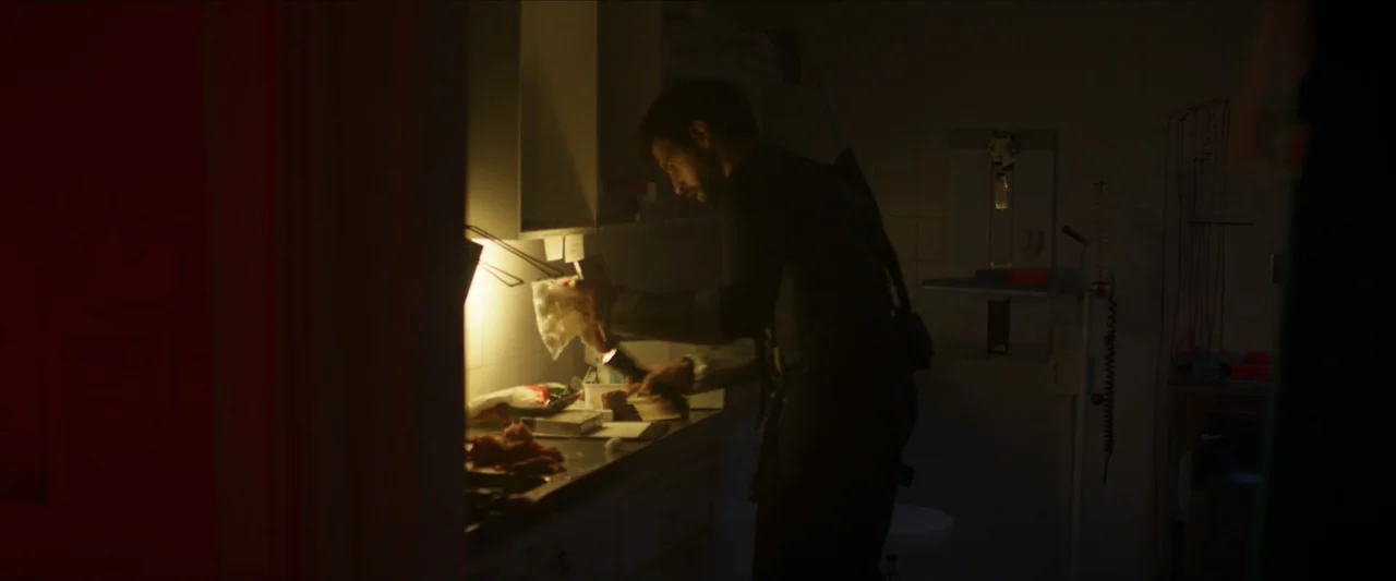 Apocalypse Z: The Beginning of the End (2024) movie still: medium — A dimly lit hospital service area with medical equipment visible on the wall. A…