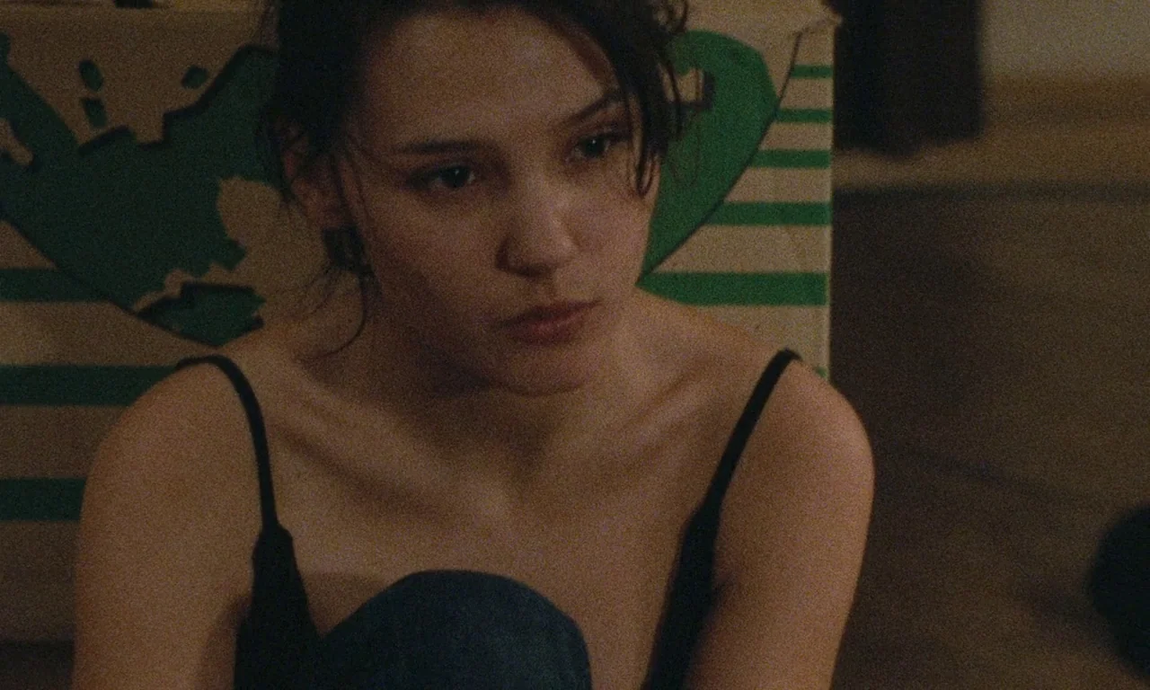 Late August, Early September (1998) movie still: closeup — A woman sits inside an apartment in front of a striped cardboard moving box. She looks…