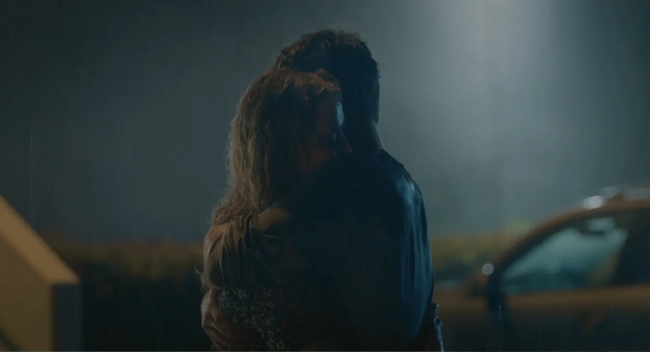 The Map of Tiny Perfect Things (2021) movie still: medium — An outdoor parking lot at night features rain falling under the glow of a streetlamp. A…