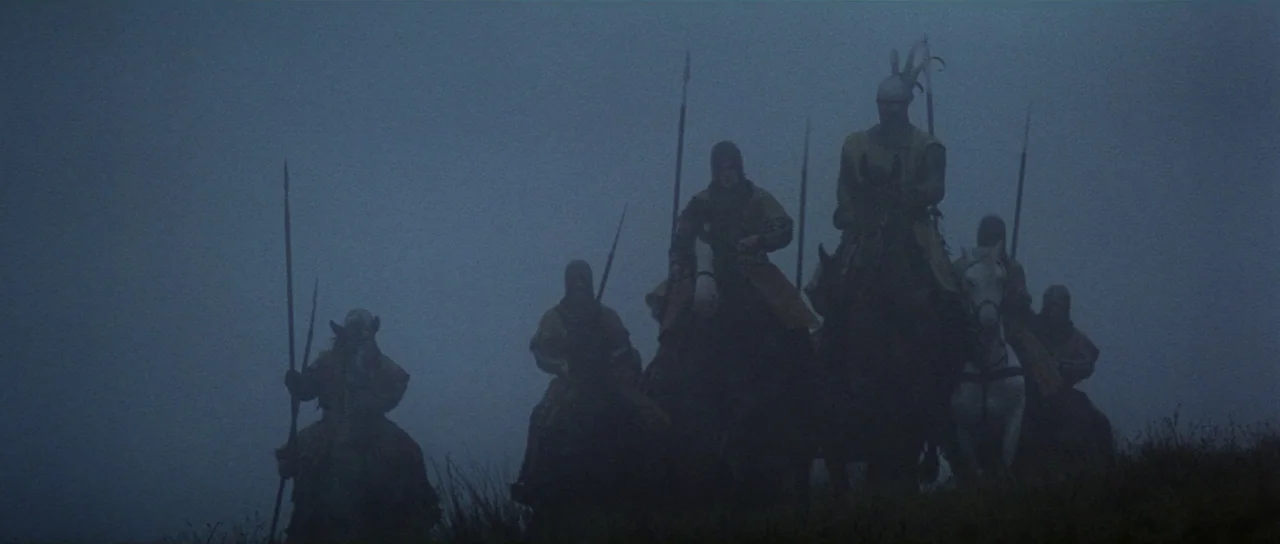 Braveheart (1995) movie still: wide — A group of armored men on horseback stand on a grassy hill in fog. The riders hold long spears upright while…