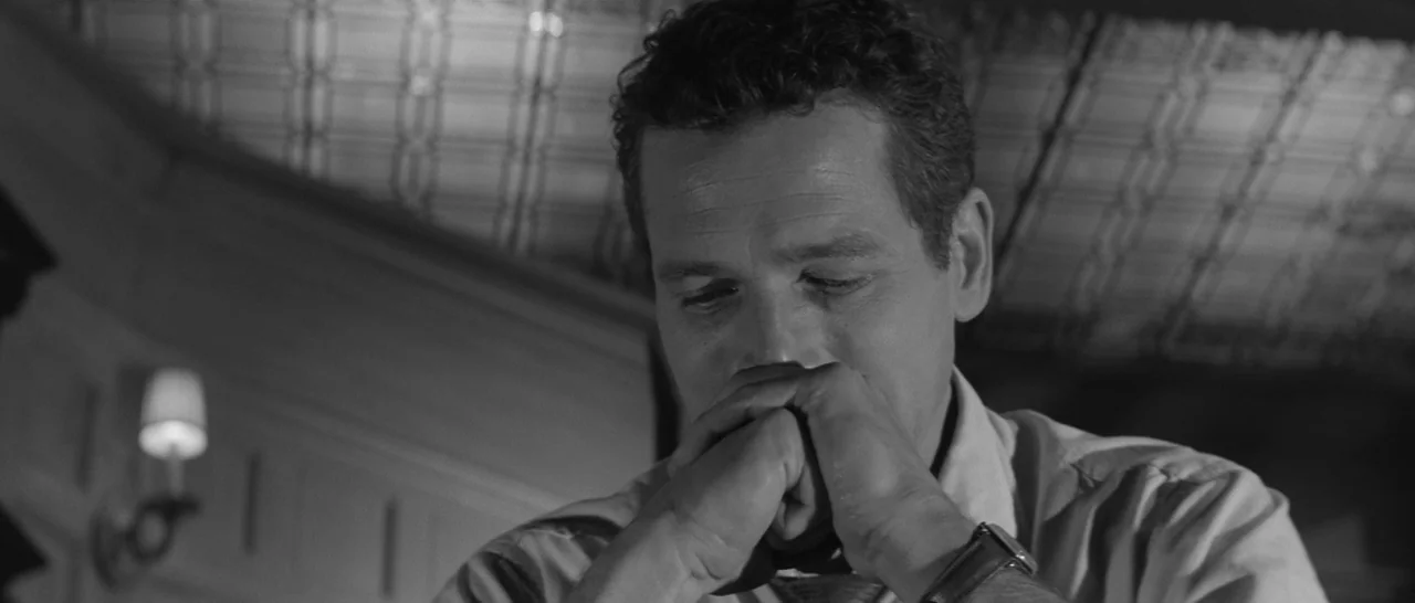 The Hustler (1961) movie still: closeup — A man in a shirt sits in a room with patterned ceiling tiles. He rests his chin upon his hands while…
