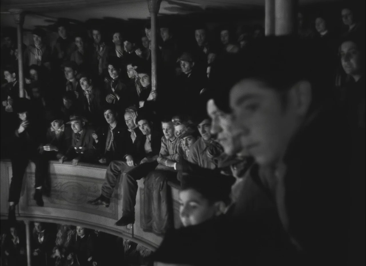 Les Enfants Du Paradis (1945) movie still: wide — A crowded theater balcony packed with people leaning over the railing to watch something. Most…