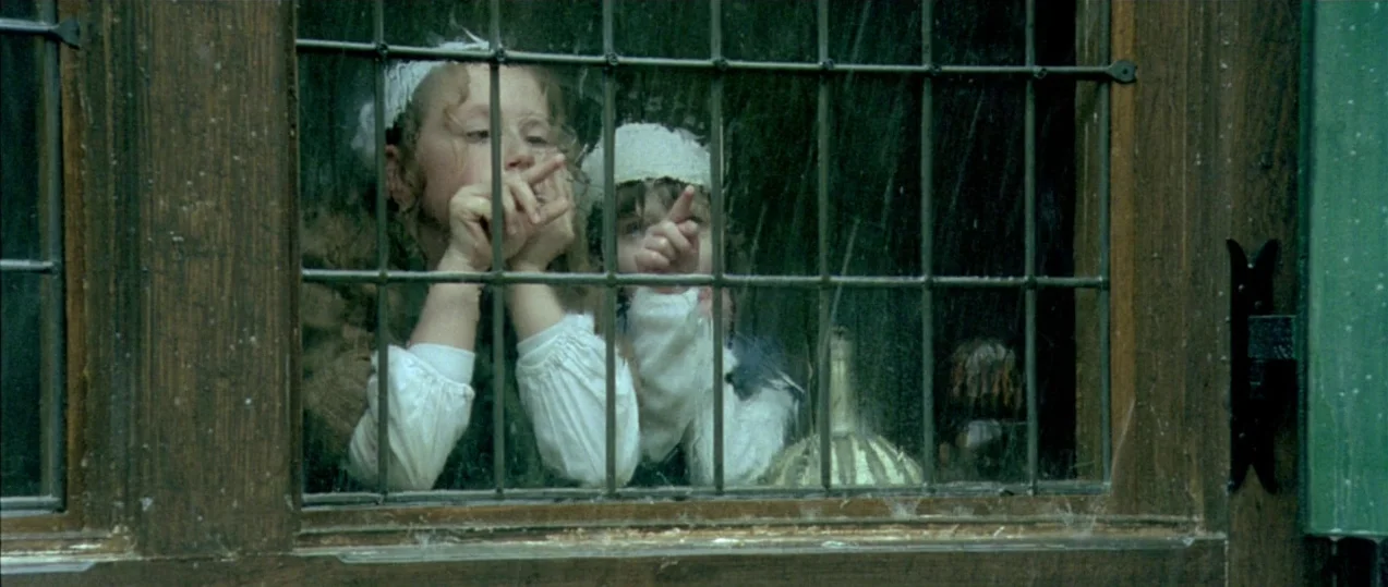 Girl with a Pearl Earring (2003) movie still: medium — Two children stand behind a wooden-framed leaded glass window looking out. They press their…