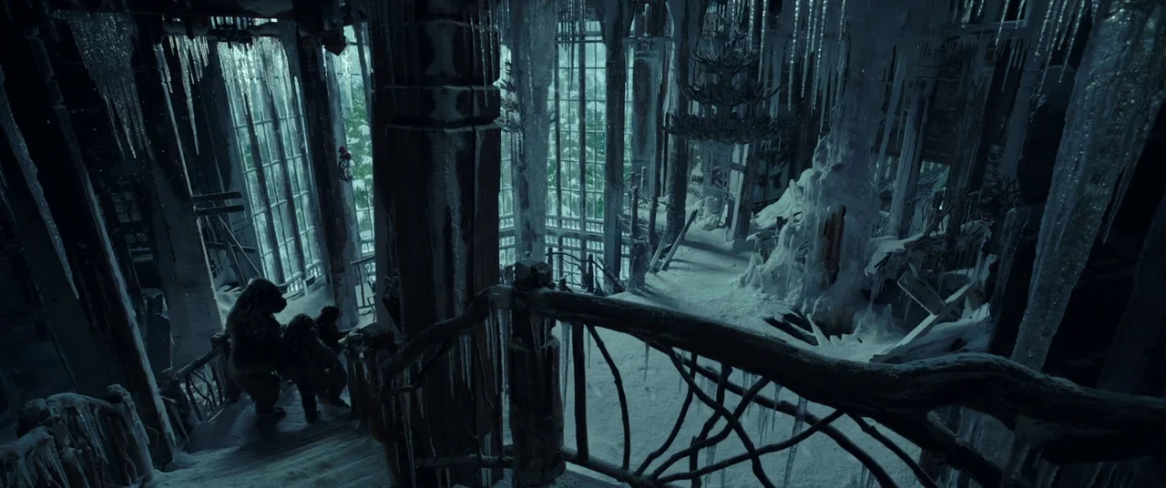 War for the Planet of the Apes (2017) movie still: wide — A dilapidated, multi-story structure is encased in thick layers of ice and icicles. Two…