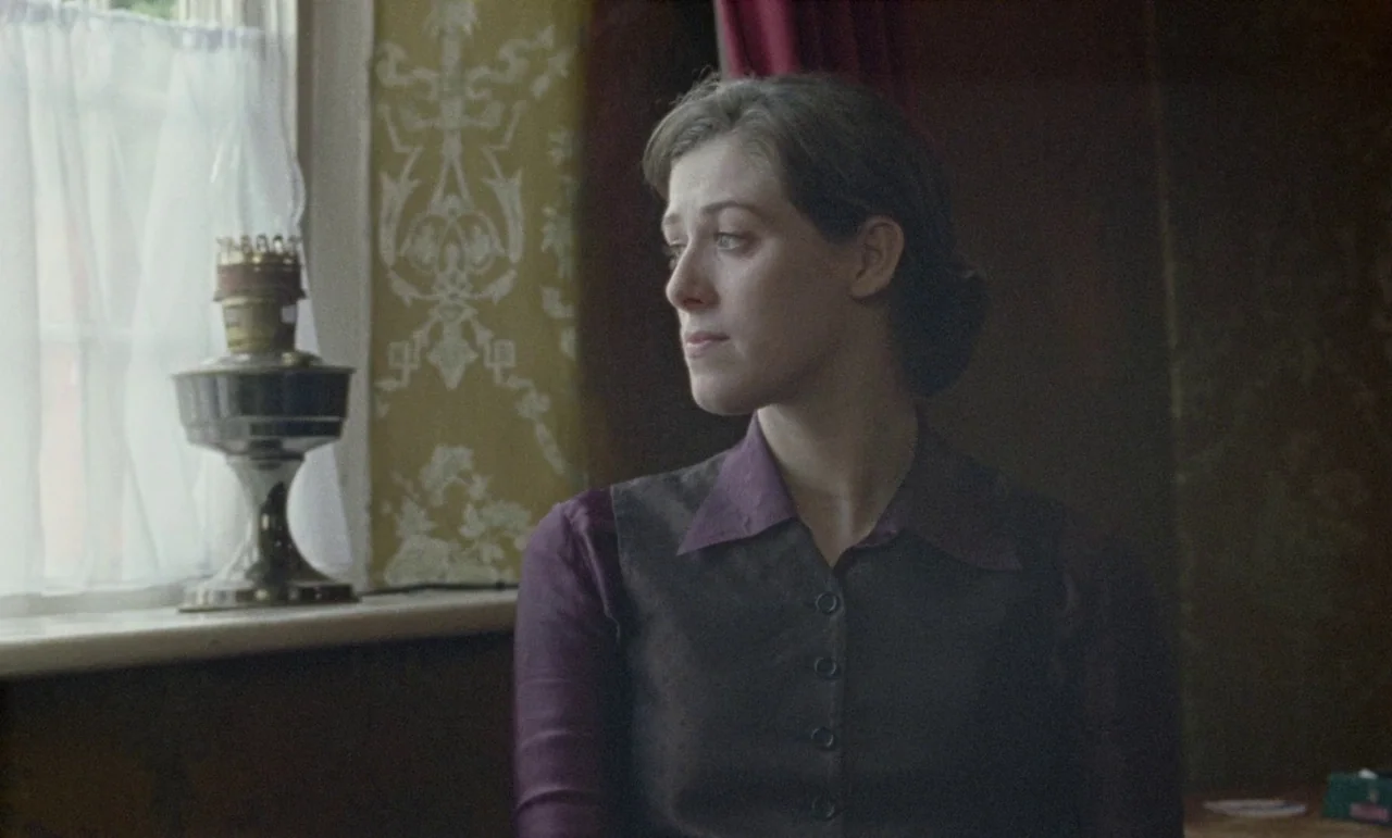 The Souvenir: Part II (2021) movie still: medium — A room with patterned floral wallpaper features a window draped with a white curtain. A woman…
