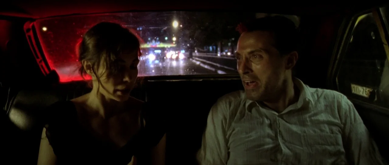 Vinyan (2008) movie still: medium — A man and a woman sit in the cramped backseat of a taxi at night. Outside the rear windshield, blurred streaks…