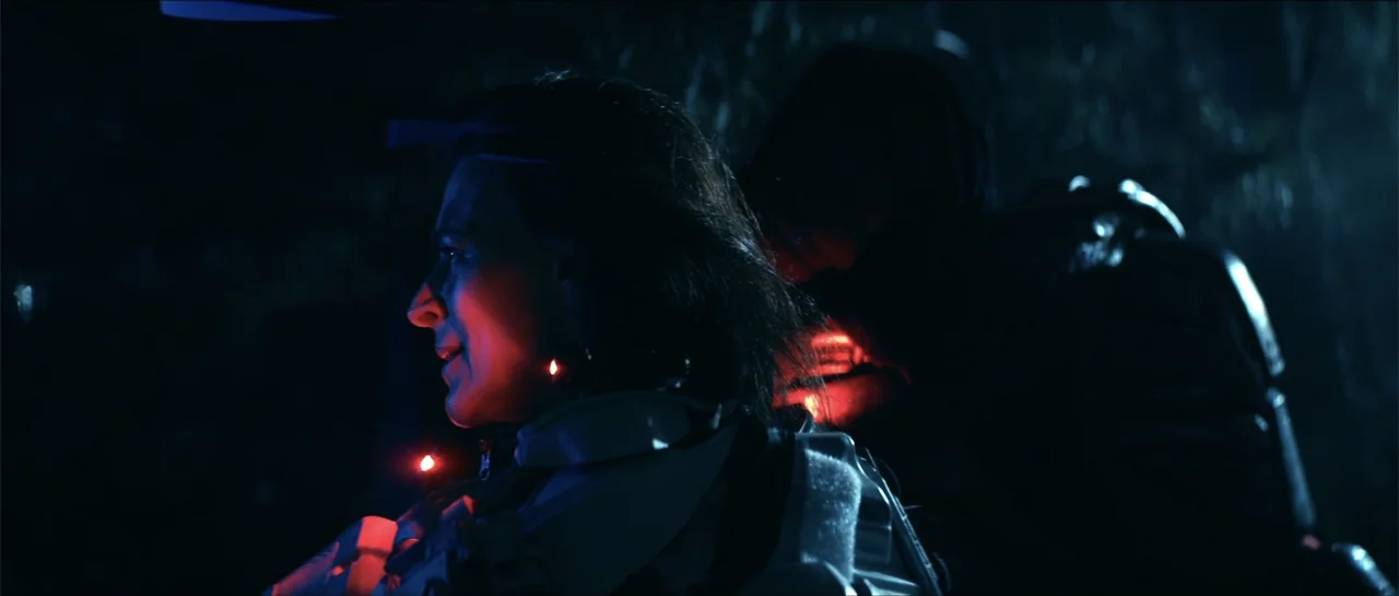 Cosmic Sin (2021) movie still: medium — A dark outdoor space at night features two people wearing white tactical armor pieces. The foreground…