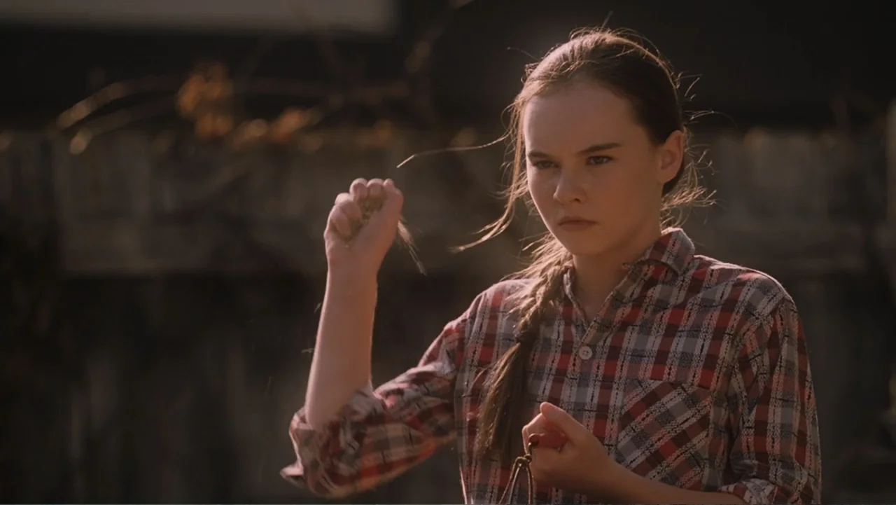 Flipped (2010) movie still: medium — A teenage girl stands outdoors during the late afternoon with light filtering behind her. She holds a small…