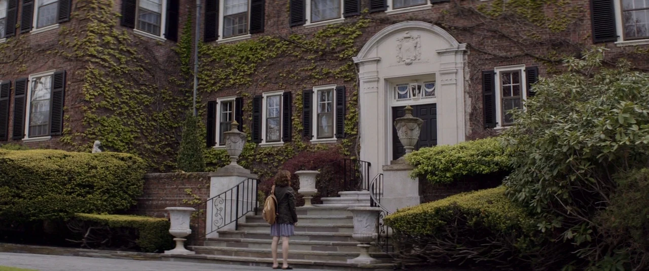 Thoroughbreds (2017) movie still: wide — An ivy-covered brick mansion features symmetrical windows and a central stone arched doorway. A person with…