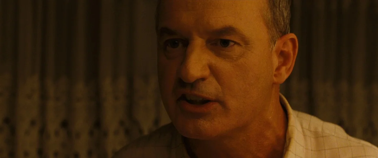 The Death and Life of John F. Donovan (2018) movie still: closeup — An interior space with a dimly lit background featuring a textured curtain…