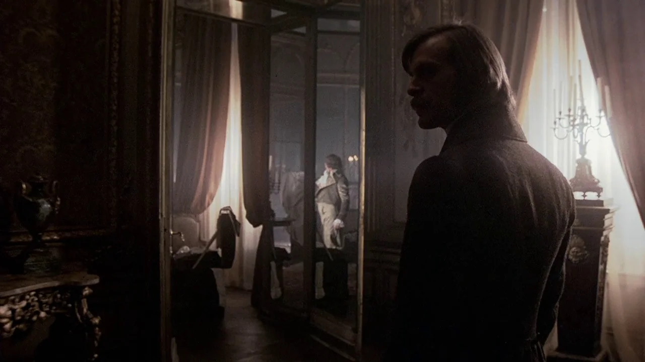 The Duellists (1977) movie still: medium — An opulent, dimly lit room contains heavy curtains, antique furniture, and a large mirror. A man looks…