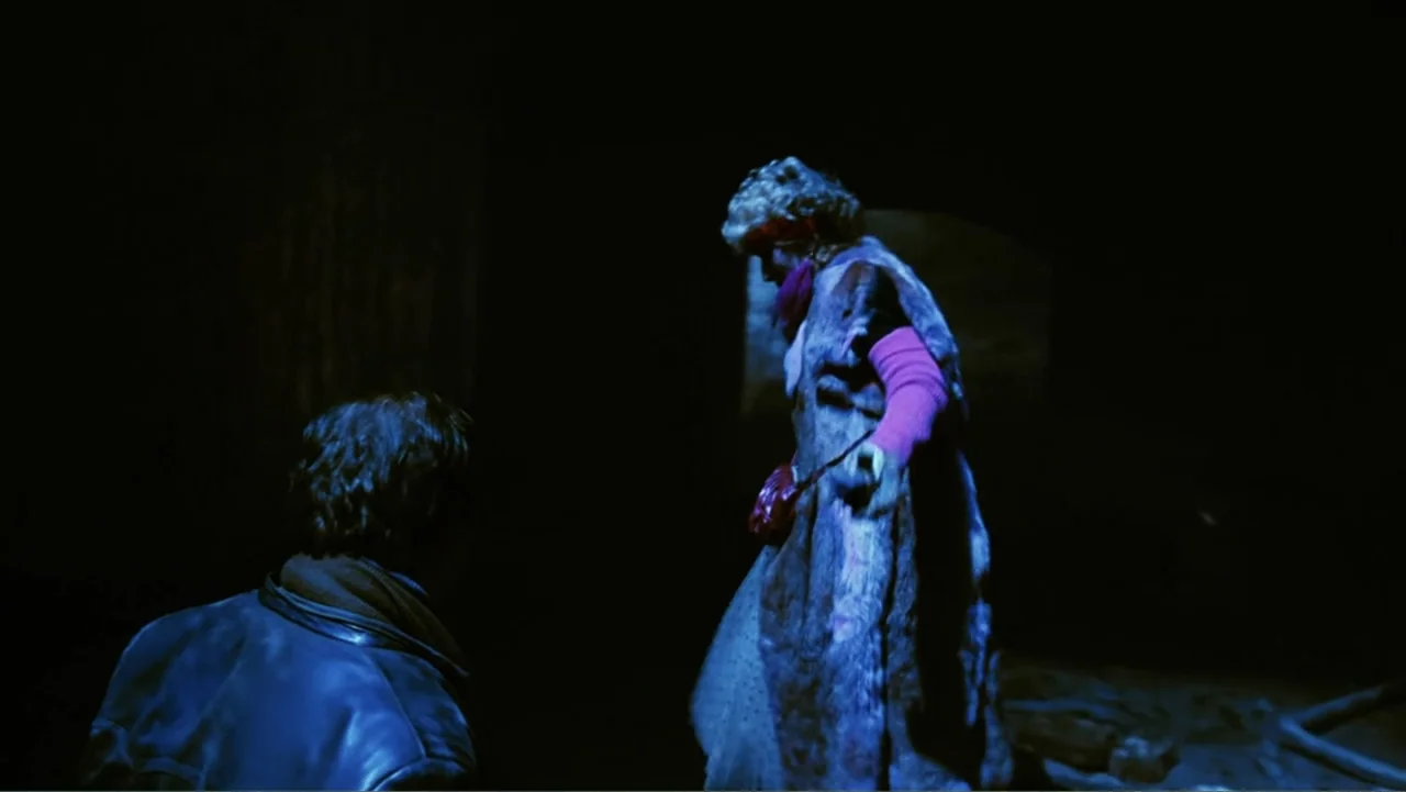 O-Bi, O-Ba: The End of Civilization (1985) movie still: medium — A dark, dimly lit interior space with shadows obscuring the surroundings. A man in…