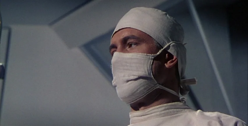Magnificent Obsession (1954) movie still: closeup — A sterile surgical room with a person in medical attire standing in the center. The subject is…