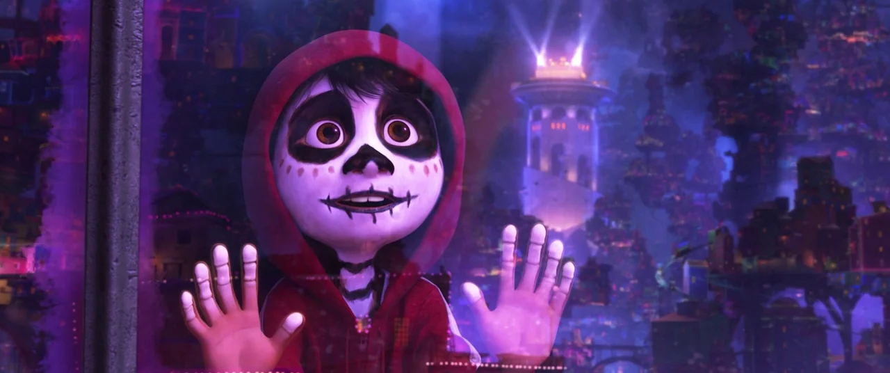 Coco (2017) movie still: closeup — A dark interior space overlooks a sprawling, illuminated fantasy city at night. A young skeleton boy presses his…