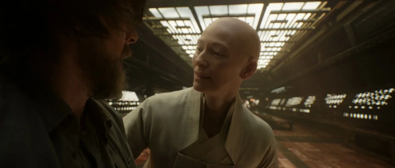 Doctor Strange (2016) movie still: medium — A spacious interior hall features geometric ceiling lights and a dark, polished wood floor. A bald…