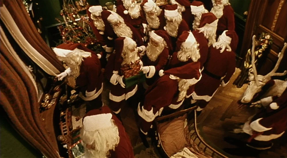 The City Of Lost Children movie still: wide — A crowded interior space features many people dressed in traditional red and white Santa suits. The…