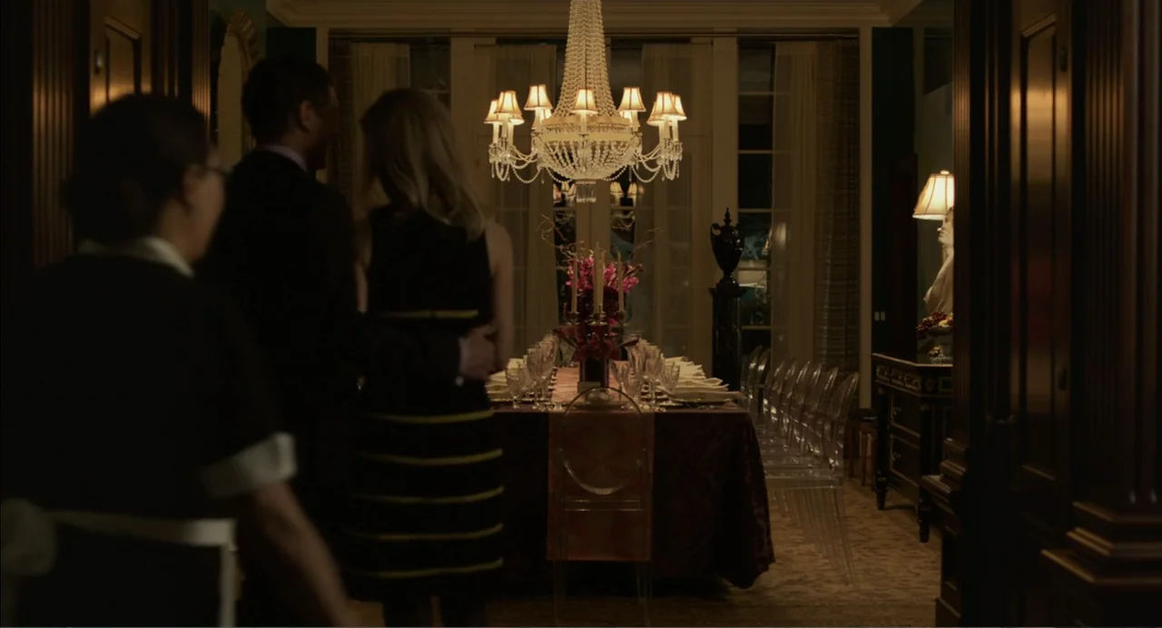 Norman: The Moderate Rise and Tragic Fall of a New York Fixer (2016) movie still: medium — A dark dining room features a long table set for many…