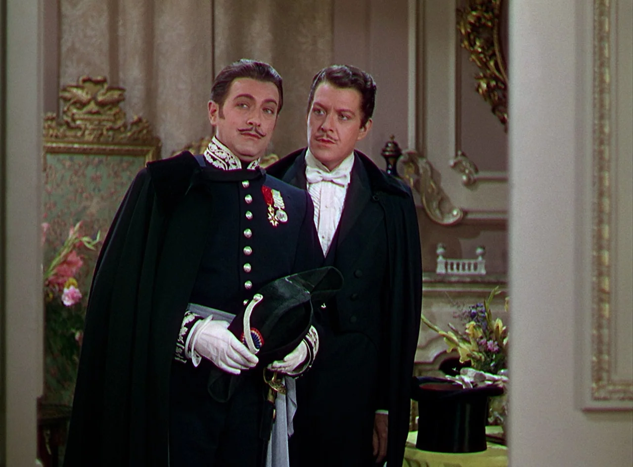 Phantom of the Opera (1943) movie still: medium — An opulent interior space with decorative wall paneling and ornate gold-framed furniture. Two men…
