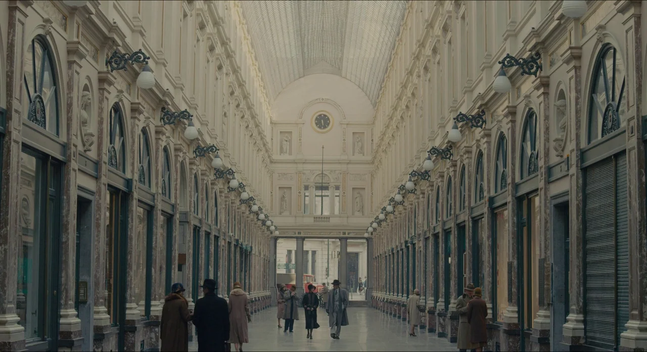 The Danish Girl (2015) movie still: establishing — An elegant 1920s shopping gallery features marble-clad columns and a vaulted glass roof. A group…
