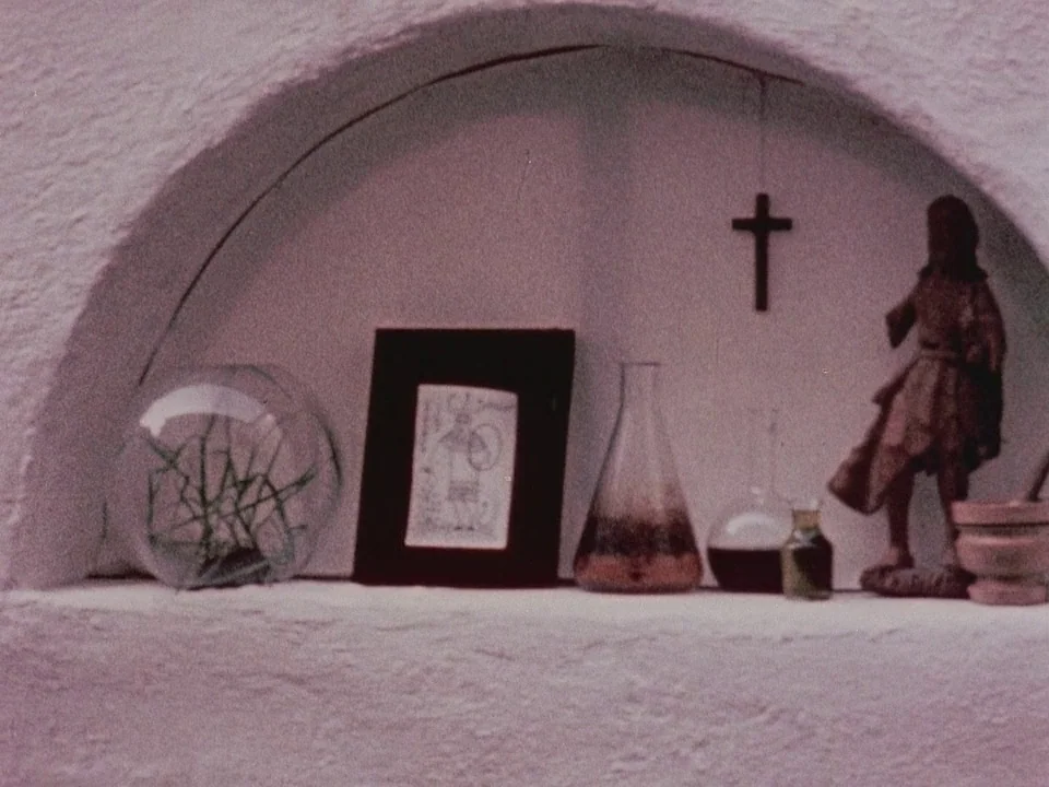 The Wormwood Star (1956) movie still: closeup — A white plastered arched niche contains various small objects arranged on a shelf. The items include…