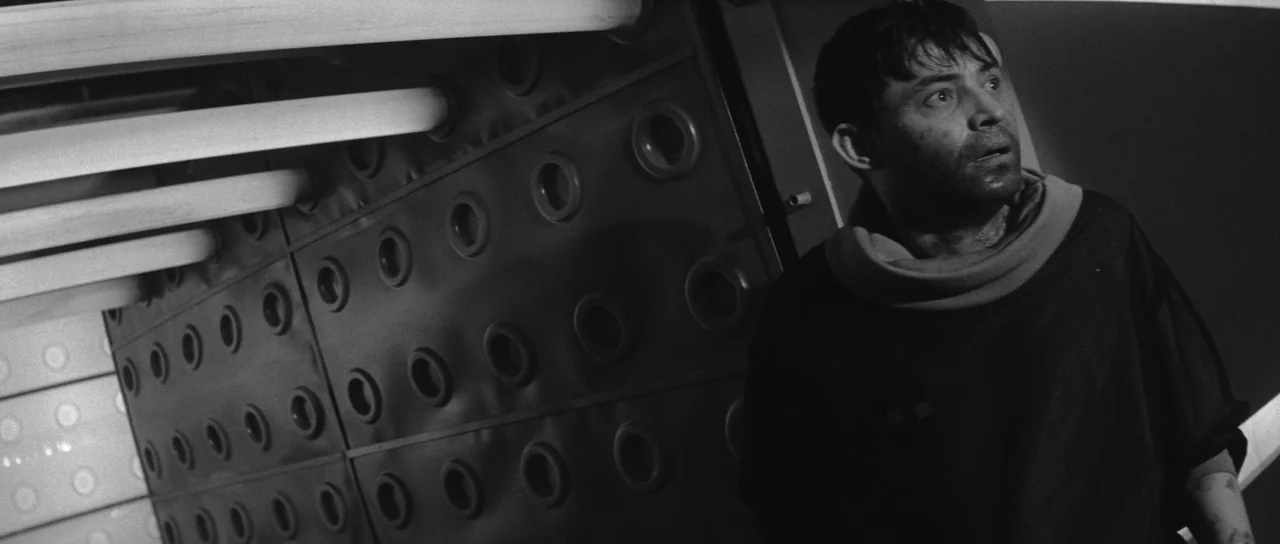 Ikarie XB 1 (1963) movie still: medium — A corridor wall features rows of circular indentations arranged in a grid pattern. A disheveled man with…