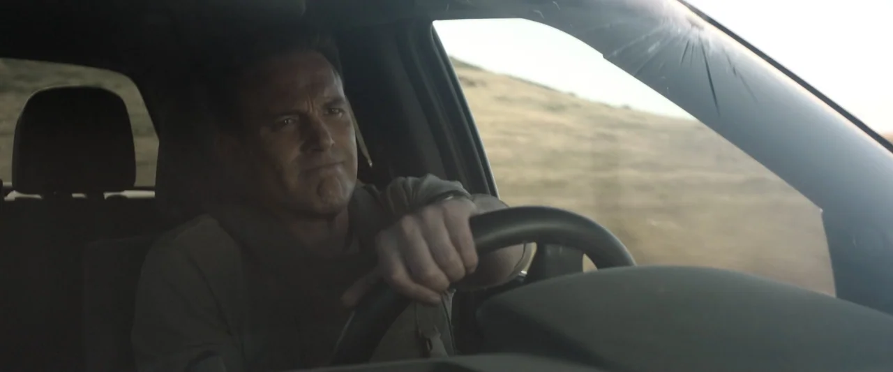 True Account: Breaking the Truce (Yakuza Bloody Chronicles 2) (2007) movie still: medium — A man drives a car along a road through dry grassy hills…