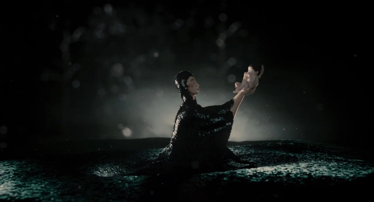 Mirror Mirror (2012) movie still: fullbody — A dark, abstract, and textured ground extends into a deep black, shadowy background. A cloaked figure…