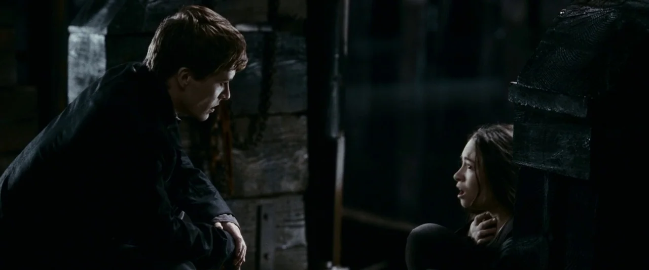 The Twilight Saga: Eclipse (2010) movie still: medium — A dark, dimly lit environment features rough wooden structures and obscured background…