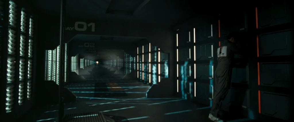 Moon (2009) movie still: wide — A dark, symmetrical futuristic corridor features numbered wall segments and repeating geometric lighting panels. A…
