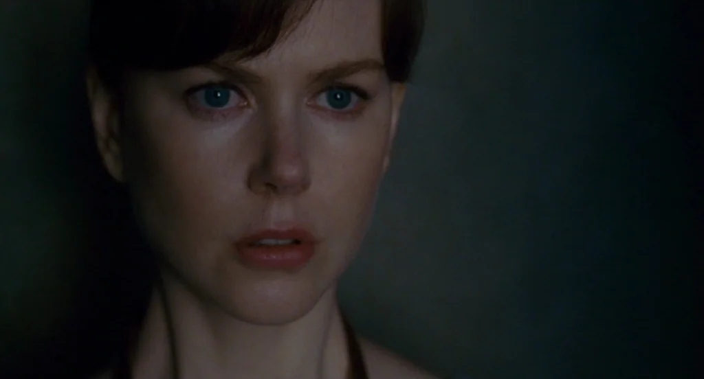 Fur: An Imaginary Portrait Of Diane Arbus (2006) movie still: closeup — A dark, nondescript interior space with minimal ambient light. A woman gazes…