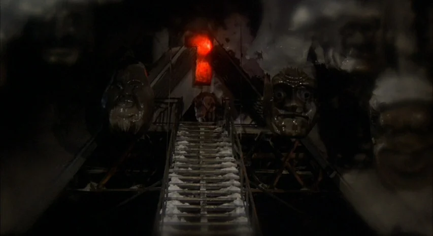 Quintet (1979) movie still: wide — A dark amusement park attraction features a central staircase leading toward a red light. Several large sculpted…