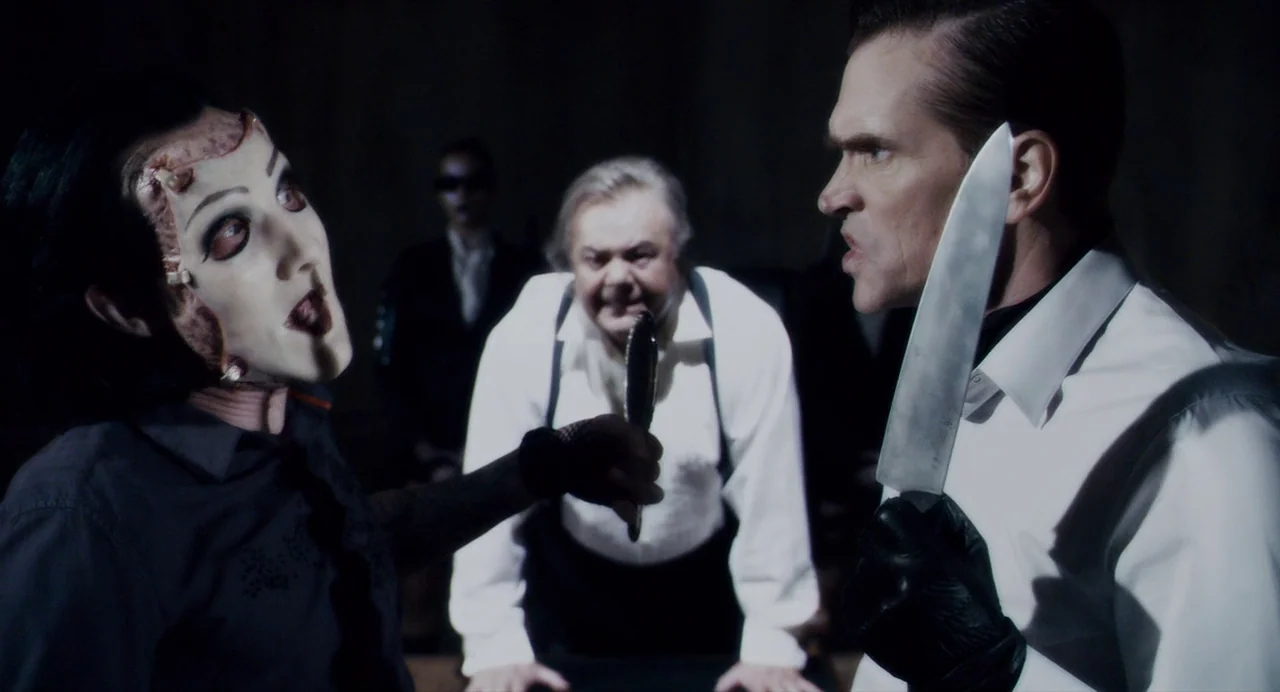 Repo! The Genetic Opera (2008) movie still: medium — A dark, nondescript room serves as the setting for an intense armed confrontation. Three men…