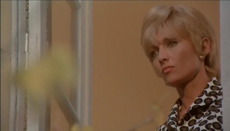 Le Boucher (1970) movie still: closeup — A woman stands in a bright room with beige walls and a window frame. The woman gazes towards the side while…