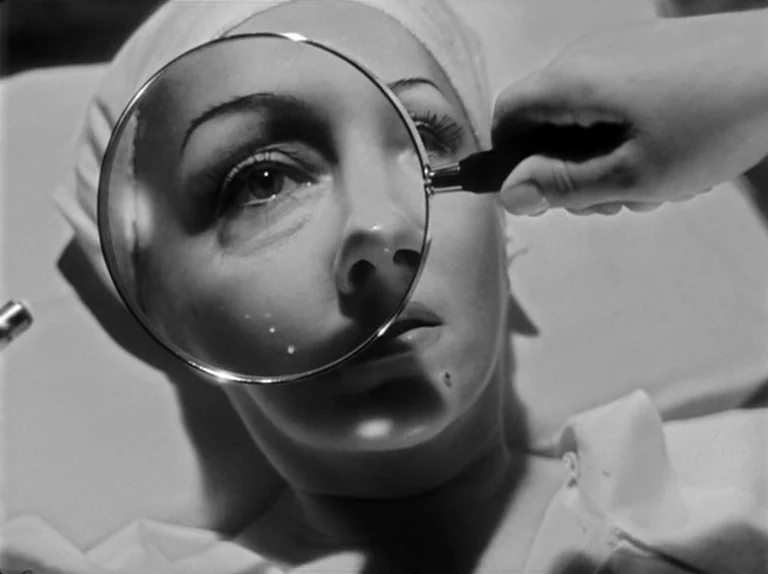 Sunset Boulevard (1950) movie still: closeup — A medical environment features a patient lying down under bright clinical lighting. A hand holds a…