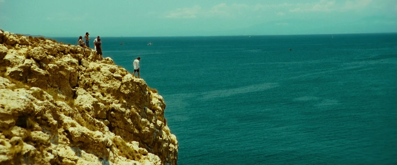 Limitless (2011) movie still: wide — A group of people gathers on the edge of a rugged yellow limestone cliff. They look out over a vast expanse of…