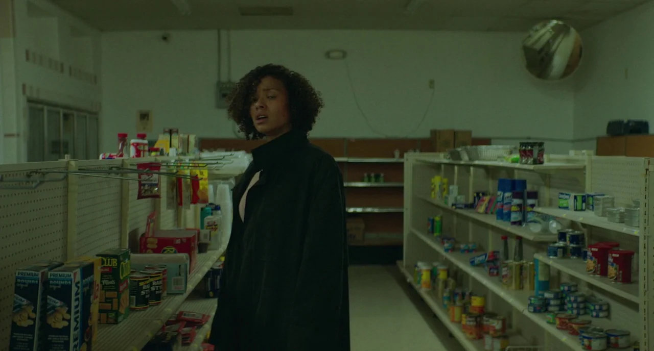 Fast Color (2018) movie still: medium — A sparsely stocked convenience store aisle features metal shelving with rows of food items. A young woman…