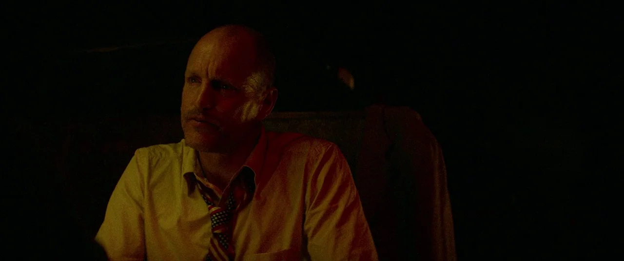 Triple 9 (2016) movie still: medium — A dimly lit room with heavy shadows obscures the surrounding environment in total darkness. A bald middle-aged…