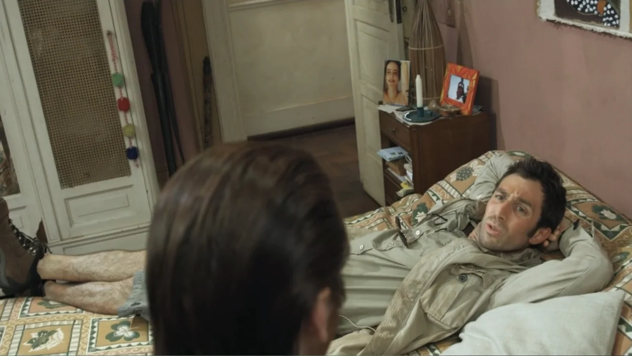 For Sale or Rent (2013) movie still: medium — A cluttered bedroom features a patterned bedspread and personal photographs displayed on a nightstand.…
