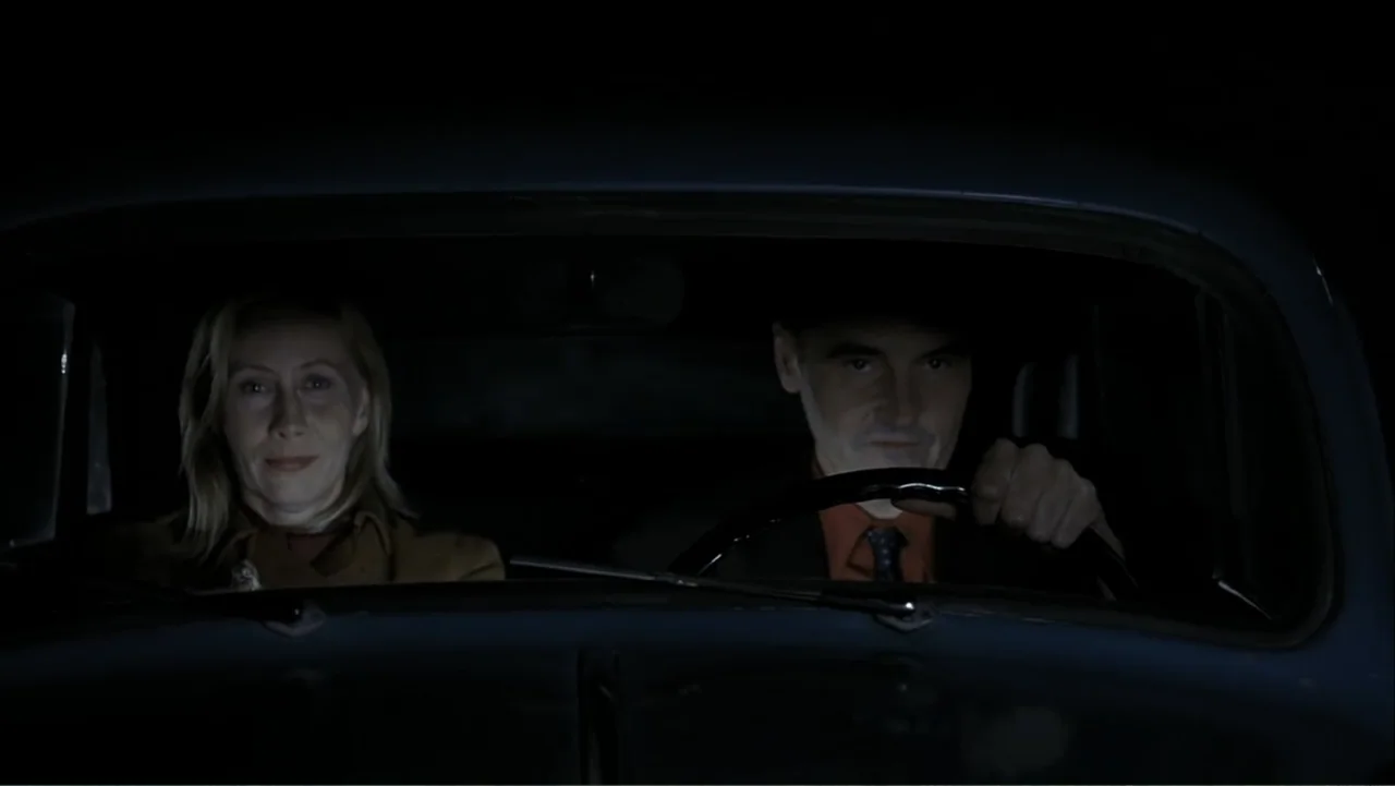 The Man Without a Past (2002) movie still: medium — A man and a woman sit in the front seats of a car at night. The man drives while the woman sits…