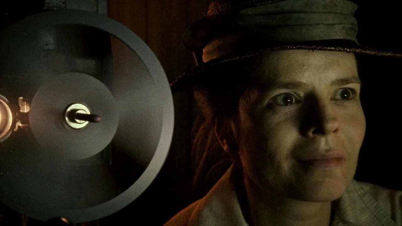 Everlasting Moments (2008) movie still: closeup — A dimly lit room focuses on a woman in a hat watching a projection. The mechanical circular reel…