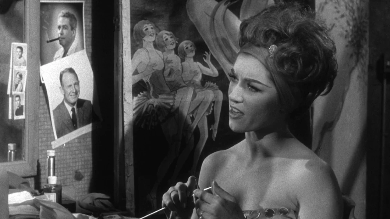 Shock Corridor (1963) movie still: medium — A cluttered dressing room table features photographs of men taped to the mirror. A woman sits in front…
