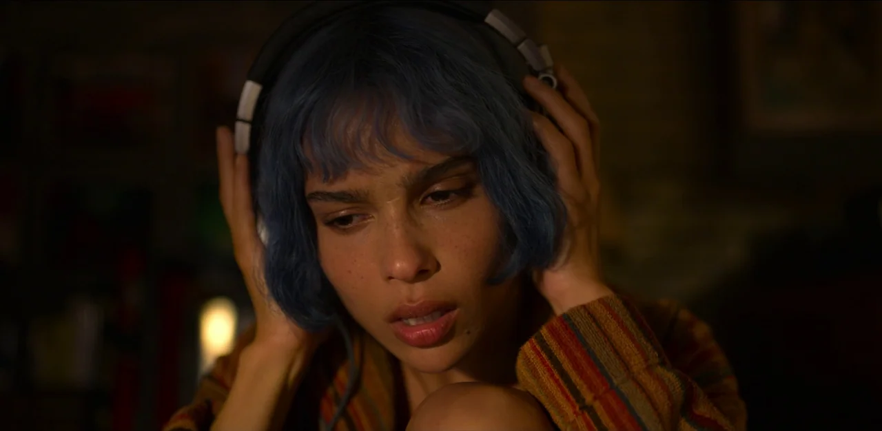 Kimi (2022) movie still: closeup — A dimly lit interior space serves as the backdrop for a close-up portrait. A woman with short blue hair wears…