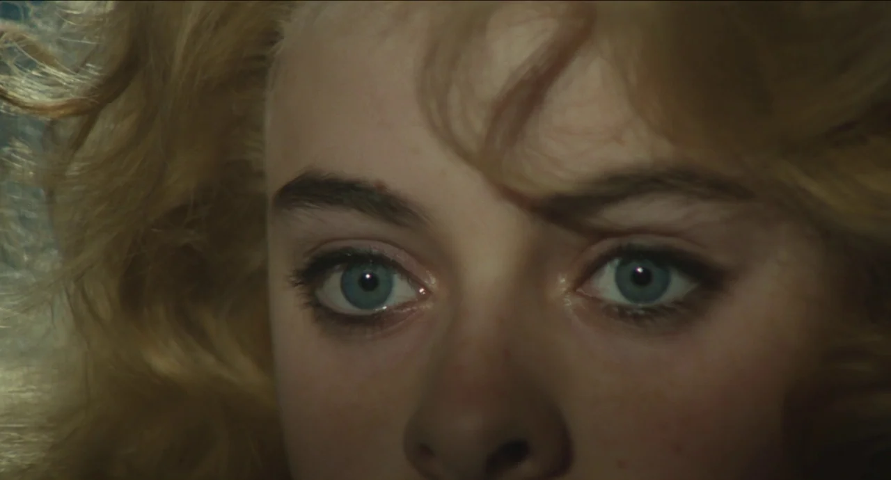 City of Women (1980) movie still: closeup — A close-up reveals the face of a young woman with wavy blonde hair. She stares ahead with intense blue…
